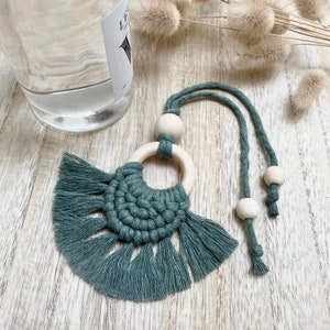 Peut inclure: Une décoration suspendue en macramé turquoise avec un anneau en bois et des perles. L'ornement est suspendu à un long cordon.