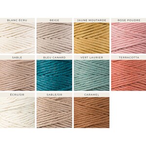 Peut inclure: Une collection de 12 bobines de cordon en coton de diff&eacute;rentes couleurs, dont beige, blanc, jaune, rose, marron, bleu, vert et rouge. Les bobines sont dispos&eacute;es en trois rang&eacute;es de quatre. Chaque bobine porte une &eacute;tiquette avec le nom de la couleur en fran&ccedil;ais.
