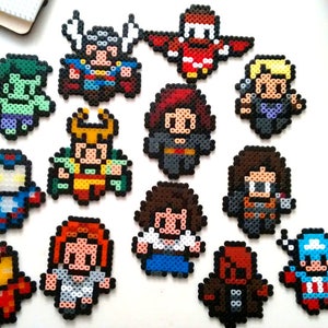 May include: A collection of 14 colorful pixel art characters, each representing a different superhero from the Marvel universe. The characters are made of small plastic beads and are arranged in a grid pattern.