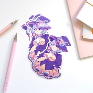 May include: Two stickers featuring a cartoon witch with blue hair, wearing a purple and pink witch hat and holding a lollipop. The witch is wearing a purple and pink striped dress with a yellow skirt.