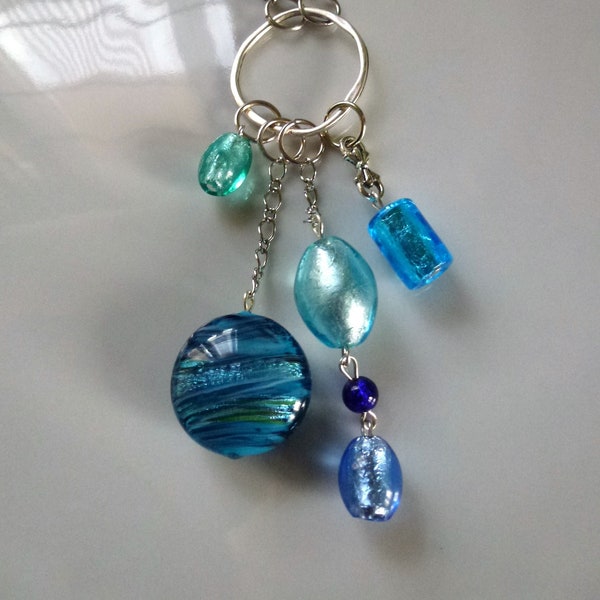 sautoir avec anneau métal argenté, perles verre de Murano ovales, cylindre, palet feuille argent bleu et vert montées sur cordon tressé noir
