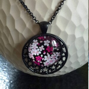 black metal medallion pattern stars with cabochon pink flowers and fuchsia on black background mounted on black metal chain