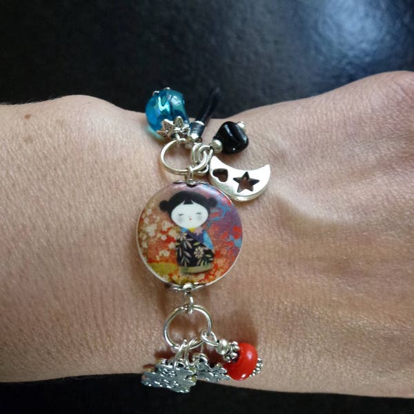 bracelet avec perle en porcelaine motif poupée japonaise, perles assorties et breloques monté sur cordon en cuir noir