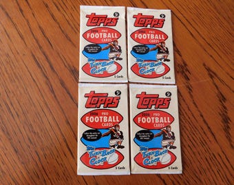 May include: Four unopened packs of 2006 Topps Pro Football cards. Each pack features a red and white oval with the words "FOOTBALL CARDS" and a football player graphic. The packs are labeled "Turn Back the Clock".