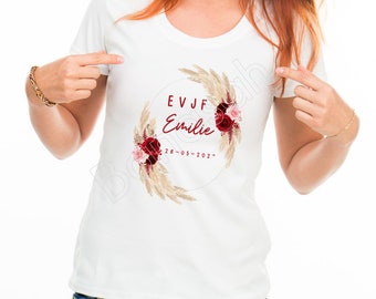 May include: White t-shirt with a red and beige floral wreath design. The wreath includes the text "EVJF Emilie 28-05-2022".