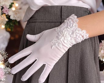 Puede incluir: Guantes blancos de satén con puño de encaje floral. Los guantes son sin dedos, lo que permite facilidad de movimiento. El encaje presenta intrincados diseños florales, agregando un toque de elegancia. Perfectos para bodas o eventos formales.