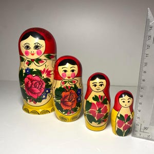 Puede incluir: Conjunto de cuatro muñecas rusas tradicionales de anidación, o muñecas matrioska. Las muñecas están pintadas en un estilo brillante y colorido con motivos florales y acentos rojos, amarillos y verdes. La muñeca más grande mide aproximadamente 18 cm de alto.
