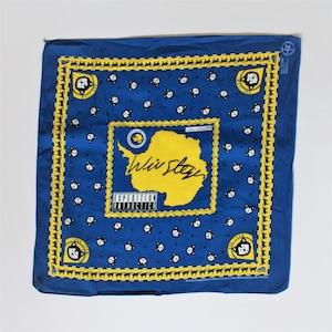 May include: Blue bandana with a yellow map of Antarctica and the text "We Stay Expedition Antarctica". The bandana is decorated with a repeating pattern of black and white dog faces.