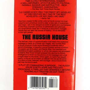 May include: A red paperback book cover with the title "The Russia House" in white text. The book is by John le Carre and features a quote from The New York Times Book Review and Vanity Fair.