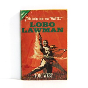 May include: A vintage paperback book cover with a red background and a cowboy holding a gun. The title is "LOBO LAWMAN" and the author is "TOM WEST".