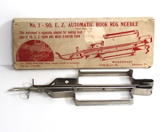 May include: A vintage metal hook rug needle in its original box. The box is labelled "No. 3 - SO. E. Z. AUTOMATIC HOOK RUG NEEDLE" and "WONDERART 2332 Byron St. Chicago, Ill."