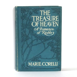 May include: A teal-colored book titled "The Treasure of Heaven" by Marie Corelli. The cover features white text and floral illustrations. The subtitle reads "A Romance of Riches". The book has a vintage aesthetic.