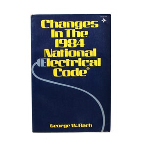 May include: A navy blue book titled "Changes In The 1984 National Electrical Code" with yellow text and a gray electrical plug graphic. The author's name, George W. Flach, is printed in yellow at the bottom.