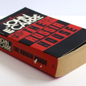 May include: A red and black paperback book titled "The Russia House" by John le Carre.