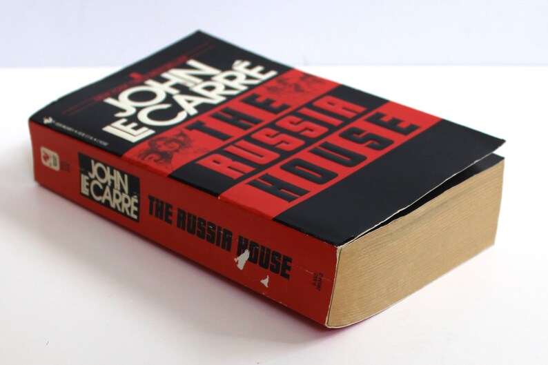 May include: A red and black paperback book titled "The Russia House" by John le Carre.