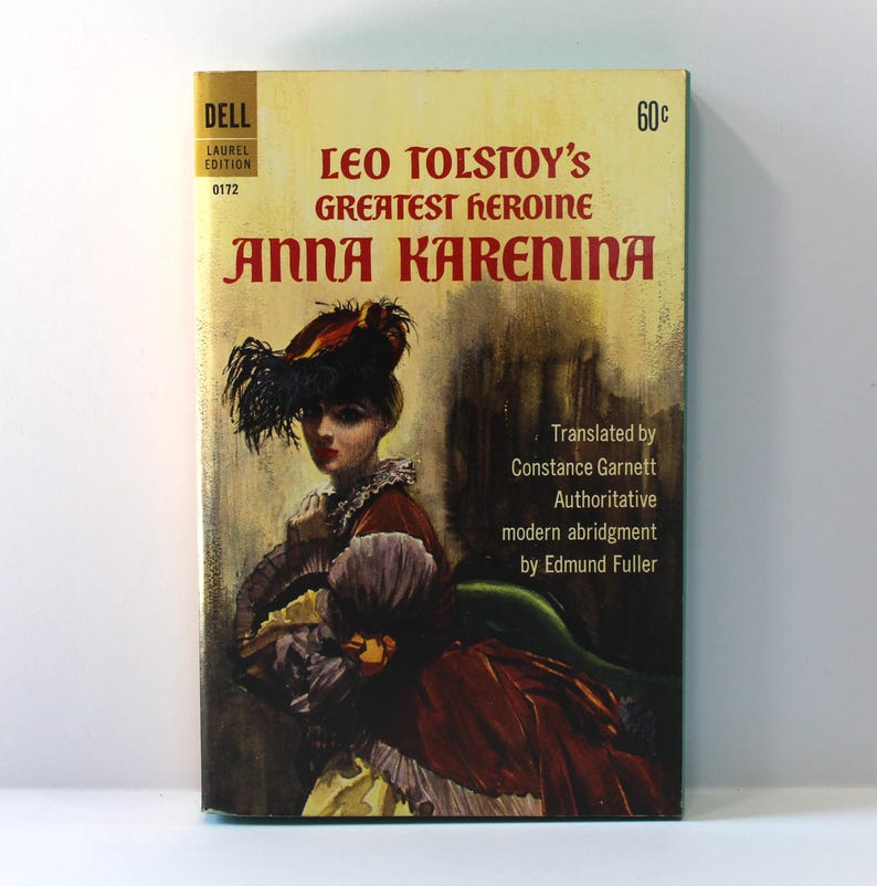 Puede incluir: Portada de libro de bolsillo vintage de "Anna Karenina" de Le&oacute;n Tolst&oacute;i. La portada presenta un retrato de una mujer con un sombrero con plumas y un vestido burdeos. El t&iacute;tulo y el nombre del autor est&aacute;n en texto rojo.