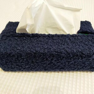 Op de afbeelding: Een donkerblauwe tissueboxhoes gemaakt van zacht, pluche materiaal. De hoes heeft een rechthoekige vorm en is ontworpen om te passen op een standaard tissuebox.