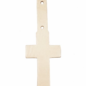 May include: A white leather cross with two holes at the top and one in the middle. The cross is a decorative piece and can be used for crafts.