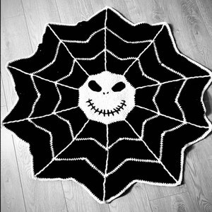May include: Black and white crocheted spiderweb rug with a white Jack Skellington face in the centre.