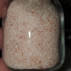 May include: A glass jar with a cork lid filled with pink Himalayan salt.