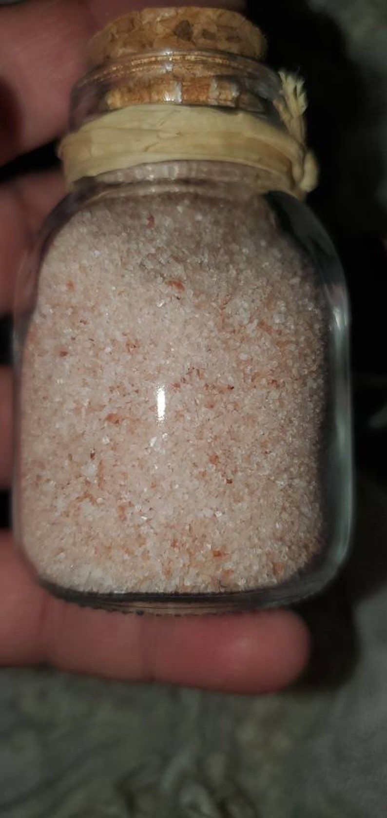 May include: A glass jar with a cork lid filled with pink Himalayan salt.