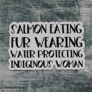 Peut inclure: Autocollant blanc avec du texte noir qui dit "Salmon Eating Fur Wearing Water Protecting Indigenous Woman".