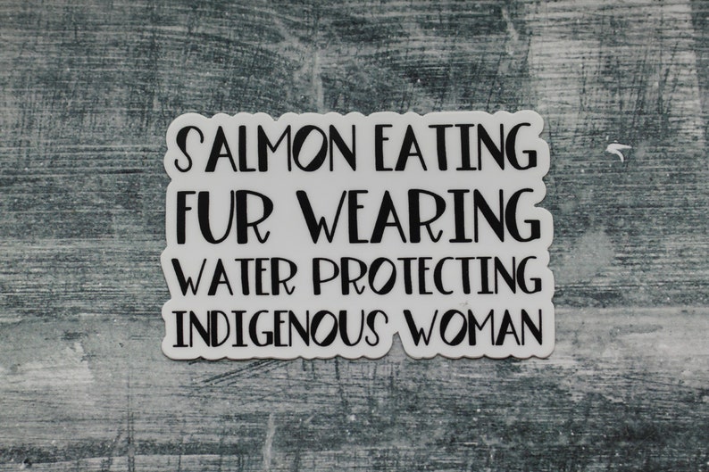 Peut inclure: Autocollant blanc avec du texte noir qui dit "Salmon Eating Fur Wearing Water Protecting Indigenous Woman".