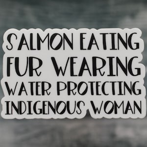 Peut inclure: Autocollant blanc avec du texte noir qui dit "Salmon Eating Fur Wearing Water Protecting Indigenous Woman".