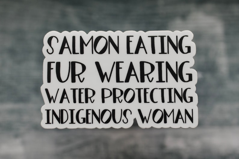 Peut inclure: Autocollant blanc avec du texte noir qui dit "Salmon Eating Fur Wearing Water Protecting Indigenous Woman".