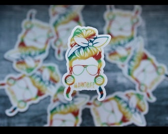 Könnte beinhalten: Ein bunter Aufkleber mit dem Gesicht einer Frau, einem unordentlichen Dutt, Sonnenbrille und Ohrringen. Der Text "#auntielife" befindet sich unter dem Bild.