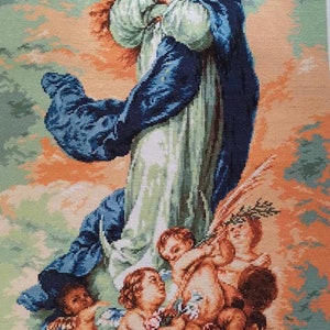 May include: Needlepoint tapestry depicting a religious scene. A woman in a blue cloak and white dress is surrounded by cherubs. The background features pastel colors and a halo effect.
