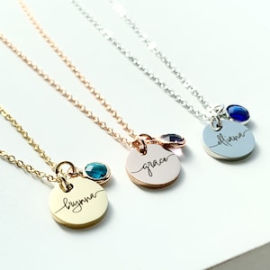 Puede incluir: Tres collares de oro, oro rosa y plata con etiquetas de nombre personalizadas y pequeños amuletos de piedras preciosas. Los nombres en las etiquetas son "Brynn", "Grace" y "Eliana".