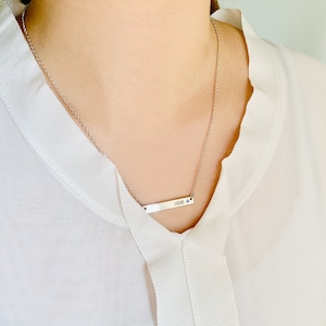 May include: A silver necklace with a bar pendant that says "LUCAS" and a small blue gemstone.