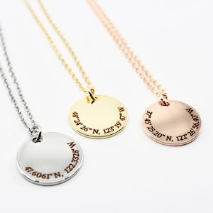 Puede incluir: Tres collares de oro, plata y oro rosa con colgantes redondos grabados con coordenadas. Los colgantes están grabados con el texto "48°24′26″ N, 123°19′47″ W", "47.6061°N, 122.3328°56.40" W" y "37°45′25.20″ N, 122°26′56.40" W".