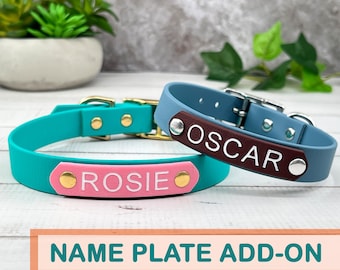 May include: Two dog collars, one teal and one blue, each with a name plate. The teal collar has a pink name plate with "ROSIE" in white. The blue collar has a brown name plate with "OSCAR" in white. Both collars have gold and silver hardware.