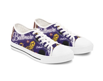 May include: White canvas low-top trainers with a purple background and a repeated pattern of footballs, players, and the word "Baltimore".