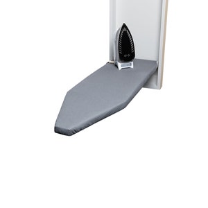 May include: A gray ironing board folds down from a cabinet door, with a black and white iron resting on top.