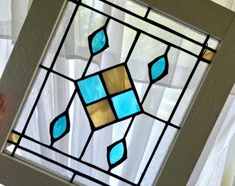 Stained glass window panel with aqua and amber colored diamonds and wood frame.
