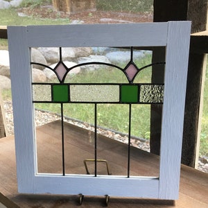 Re-made old stained glass window panel with two pink flowers with a white frame.