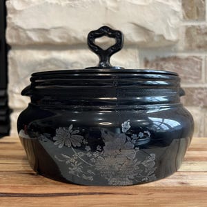May include: Black glass jar with a silver floral design and a black metal lid with a handle.