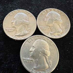 May include: Three silver US quarter dollar coins from 1967, 1968, and 1969. Each coin features the profile of Lady Liberty with the inscription "LIBERTY" above and "IN GOD WE TRUST" below. The year of minting is inscribed on the bottom of each coin.