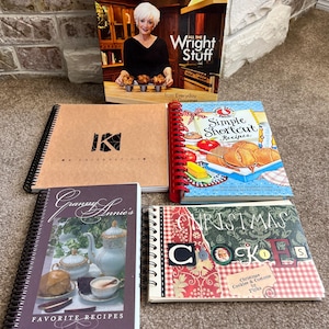 May include: A collection of cookbooks with various themes, including "All the Wright Stuff", "Simple Shortcut Recipes", "Granny Annie's Favorite Recipes", and "Christmas Cookies & Customs".
