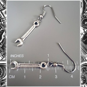 May include: Silver wrench earrings with a hook closure. The earrings are approximately 1.5 inches long.