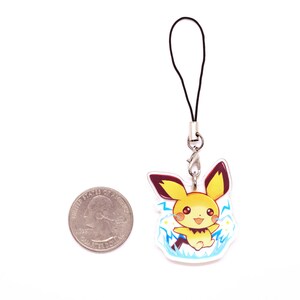 May include: A yellow and brown cartoon character with a black tail and ears, surrounded by blue lightning bolts, is printed on a clear plastic charm. The charm is attached to a black string and a silver metal clasp.