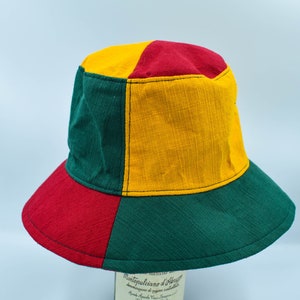 May include: A green, red, and yellow bucket hat. The hat is made of a woven fabric and has a wide brim.
