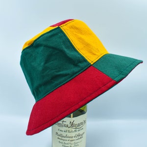 May include: A green, yellow, and red bucket hat with a contrasting stitch detail. The hat is made of a soft, textured fabric.