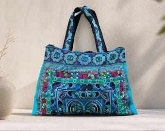 May include: A tote bag featuring intricate embroidery in shades of blue, turquoise, and purple. The design includes geometric patterns, floral motifs, and spiral details. It has two matching fabric handles and a rectangular base structure.