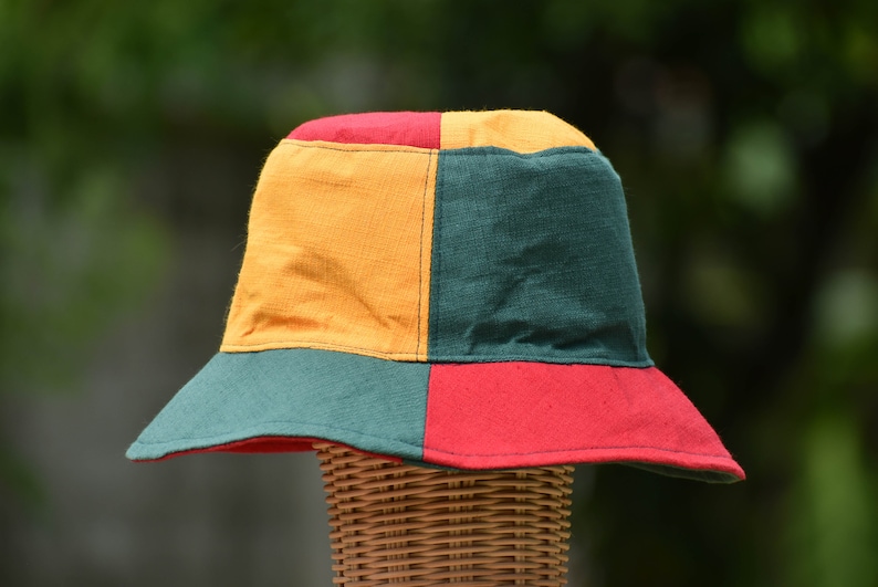 May include: A colorful bucket hat with a green, red, and yellow patchwork design. The hat is made of a soft, woven fabric.