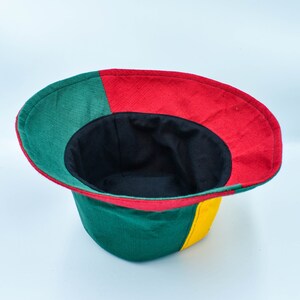 May include: A green, red, and yellow bucket hat with a black lining. The hat is turned inside out, showing the lining.