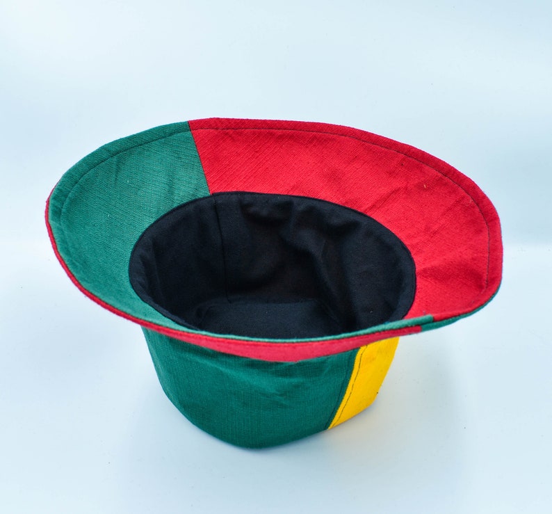 May include: A green, red, and yellow bucket hat with a black lining. The hat is turned inside out, showing the lining.
